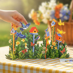 Colorful birdhouse and bird figurine set on a decorative table with flowers in the background.