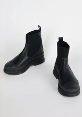 A pair of black boots with elastic ankle, rubber cap toe and chunky lug sole.