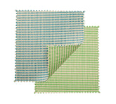 The Kim Seybert Duet Placemat Set of 4 in Blue & Green features reversible mats with blue-beige stripes on one side and green-beige on the other, shown with a folded corner—ideal for creative table settings.
