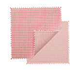 Two square fabric swatches in blush and pink with zigzag edges overlap, one partly folded to reveal both sides, highlighting the chic design of the Kim Seybert Duet Placemat Set of 4 - Blush & Pink.