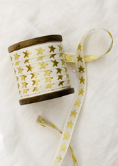 A walnut wood spool with cream ribbon with gold embroidered star pattern.