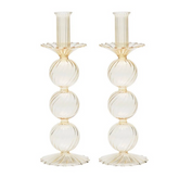 The Kim Seybert Iris Candlestick Holder Set of 2 features elegant hand-blown glass, each with three stacked ribbed spheres and scalloped base and top in a light beige or champagne hue.