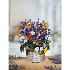 Bouquet of flowers with butterflies in a white basket on a wooden surface.