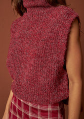A woman wearing a sleeveless turtleneck sweater in wine red.