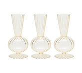 The Kim Seybert Tess Bud Vase Set of 4 in Champagne features identical translucent vases with round bases, fluted bottoms, narrow necks, and vertical ribbed lines, arranged side by side on a white background.