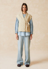 A tie front vest in cream with quilted texture and sash tie front.