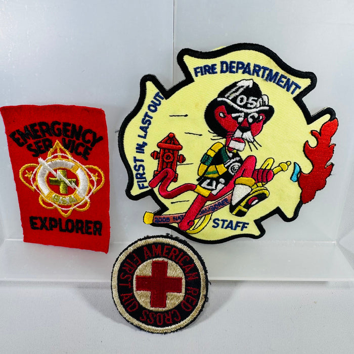 Three patches: a red 'Explorer' patch, a yellow 'Fire Department Staff' patch with a cartoon character, and a round 'American Red Cross' patch.