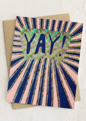A greeting card with holographic sunburst print, text reads "YAY!".