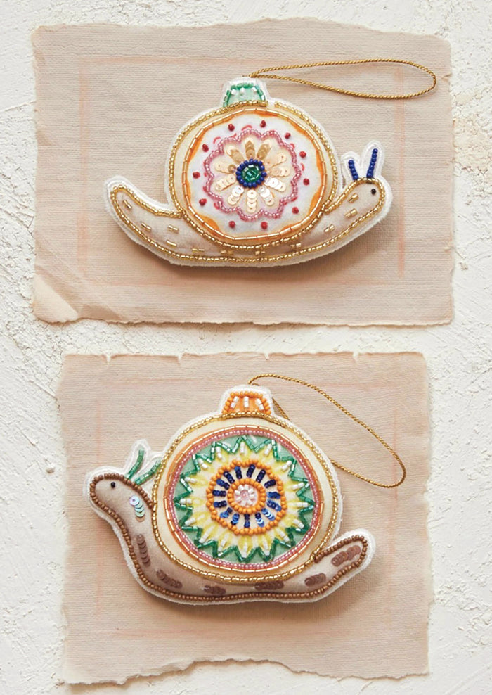 Fabric ornaments in the shape of a snail with decorative bead and sequin detailing.