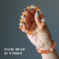 hand holding two carnelian braclets showing each bead is unique