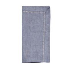The Kim Seybert Classic Napkin - Dusty Blues (Set of 4) features a folded light blue cloth with a decorative stitched border, shown against a white background.