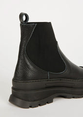 A pair of black boots with elastic ankle, rubber cap toe and chunky lug sole.