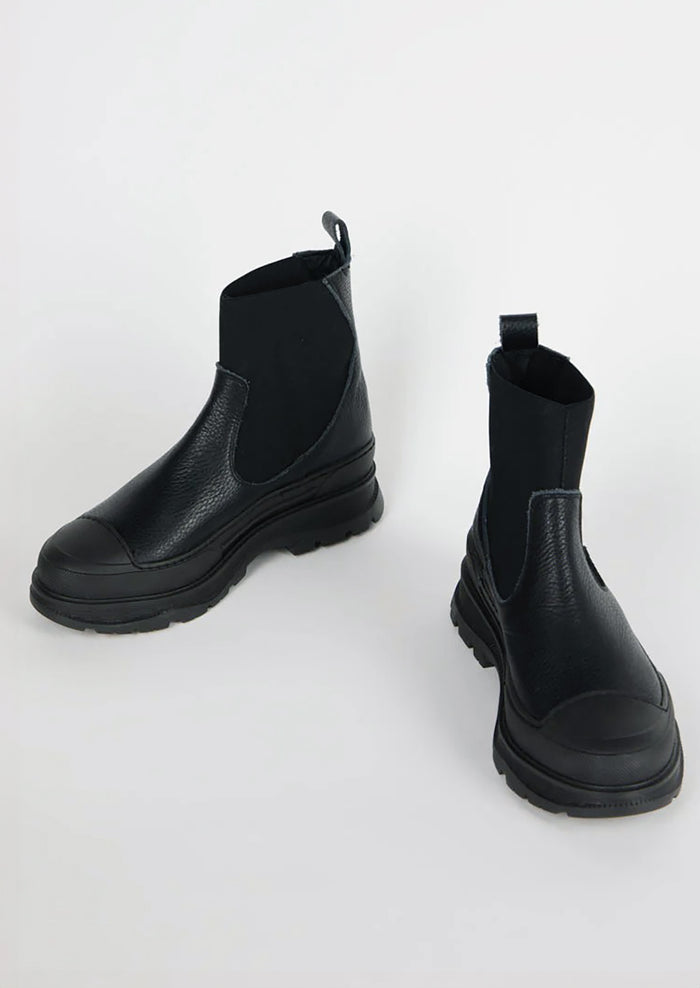 A pair of black boots with elastic ankle, rubber cap toe and chunky lug sole.