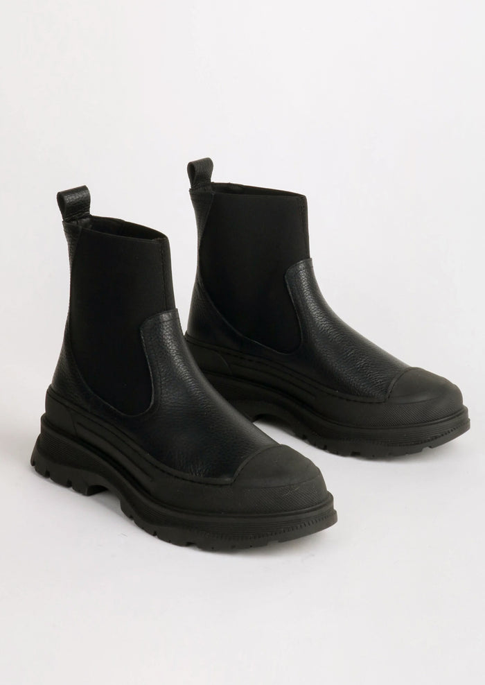 A pair of black boots with elastic ankle, rubber cap toe and chunky lug sole.