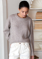 A woman wearing a round neck sweater with ribbed hem and cuffs.