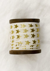 A walnut wood spool with cream ribbon with gold embroidered star pattern.