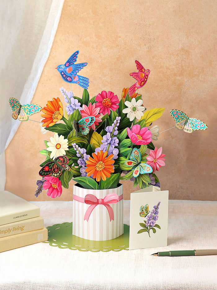 3D floral arrangement with butterflies and a card on a table