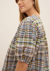 A woman wearing a plaid blouse with ruching details.