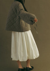 A woman wearing a quilted, padded jacket in army green with tie detail at wrists.