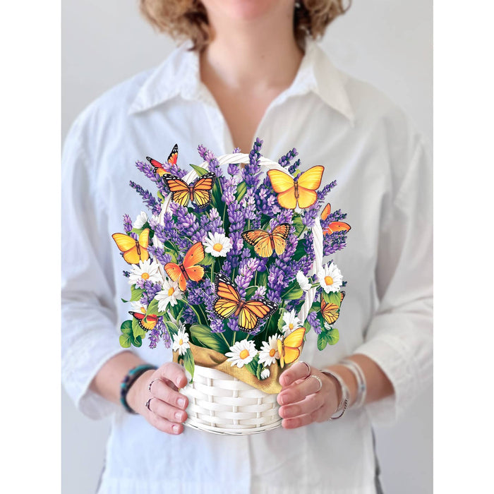 Person holding a basket of flowers with butterflies against a white background