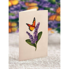 Card with a butterfly and lavender design on a textured surface with a blurred floral background.