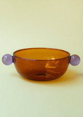 An amber glass bowl with lilac ball detail on sides.