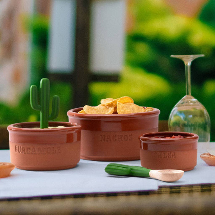 Terracotta containers with 'Guacamole', 'Nachos', and 'Salsa' text on a table outdoors.