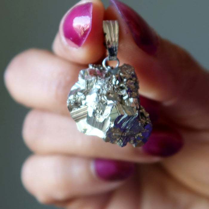 Hand holding a Pyrite crystal pendant with a blurred background