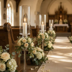 White vigil candles in glass holders lining elegant church wedding aisle