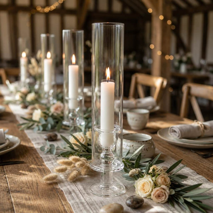 White vigil candles in glass holders on rustic floral dinner table centerpiece