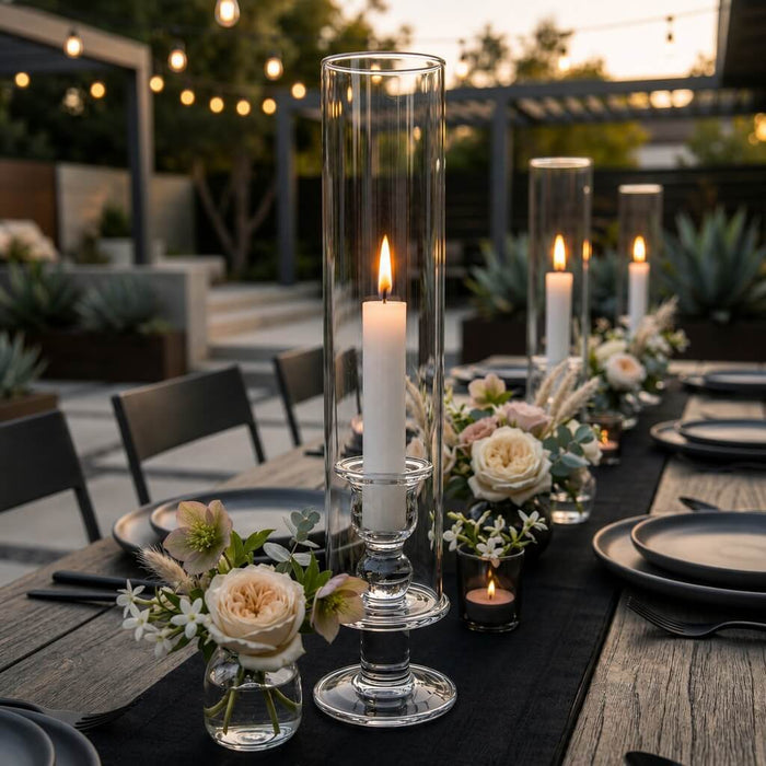 White vigil candles in tall glass holders on elegant outdoor dinner table centerpiece