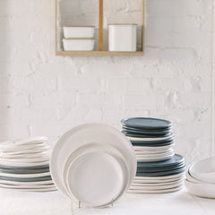 A variety of stoneware dinnerware including plates and bowls in different sizes, prominently displayed white plates.