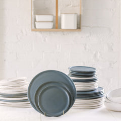 A variety of stoneware dinnerware including plates and bowls in different sizes, prominently displayed blue plates.