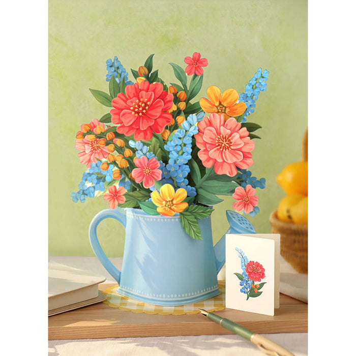 Colorful flowers in a blue watering can on a wooden surface with a green background