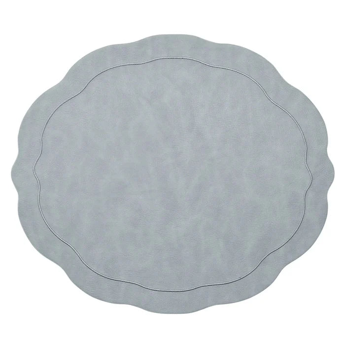 The Kim Seybert Tailored Placemat Set of 4 in Steel Grey features a light steel gray color, wavy edges, a subtle textured pattern, and an oval-shaped embossed border near the center.