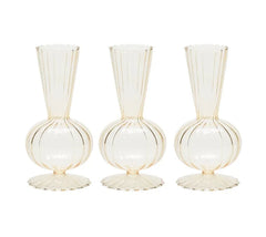 The Kim Seybert Tess Bud Vase Set of 4 in Champagne features identical translucent vases with round bases, fluted bottoms, narrow necks, and vertical ribbed lines, arranged side by side on a white background.
