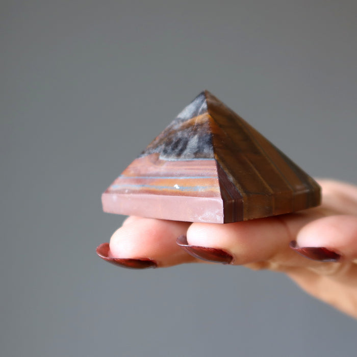 hand holding tiger iron pyramid