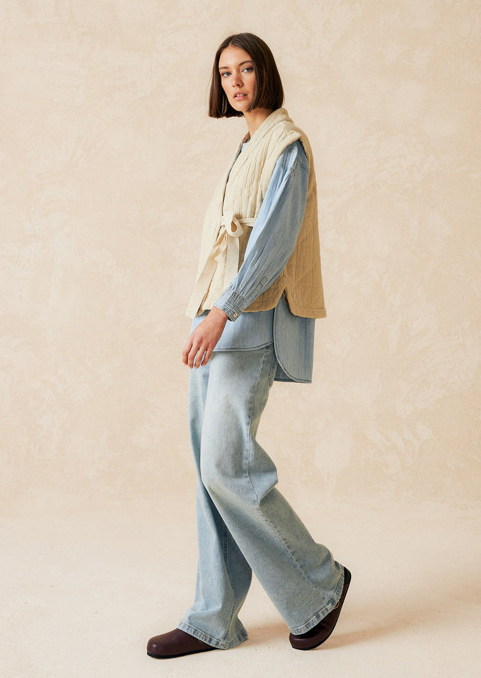 A tie front vest in cream with quilted texture and sash tie front.