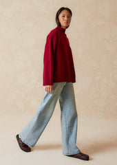 A woman wearing an oversized mockneck sweater.