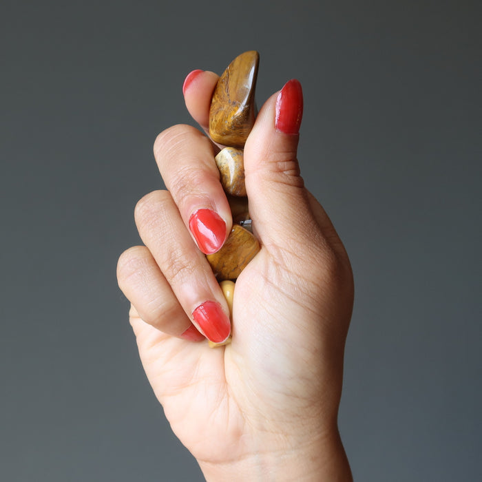 hand holding yellow jasper tumbled stones